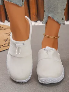 Detail of white casual loafers with drawstring closure and thick sole worn by model.