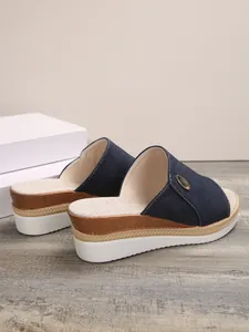 Vue détaillée de la semelle compensée multicouche et de la bride en jean de ces mules
