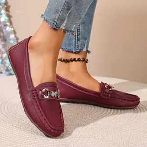 Detailed view of wine red leather loafers with decorative metal buckle ornament.