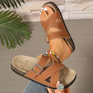 Detail view of brown crossover strap cork slides featuring silver metal buckle for women.