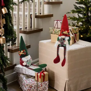 Handmade plush Christmas gnomes with long legs sitting on gift boxes for festive decor