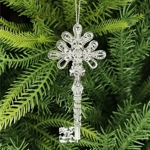 Clear acrylic Christmas ornament in the shape of an ornate vintage key hanging on a tree.