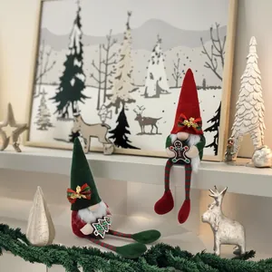 Two handmade Christmas gnome dolls sitting on a white shelf with festive winter decor
