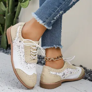 Primer plano de los zapatos Brogue con estampado floral para mujer en beige y blanco.