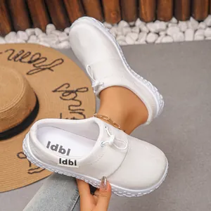 Close-up of white soft leather wedge loafers with lace-up detail and platform sole.