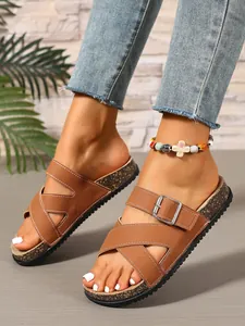 Close-up of brown cork slides with cross straps and adjustable buckle detail