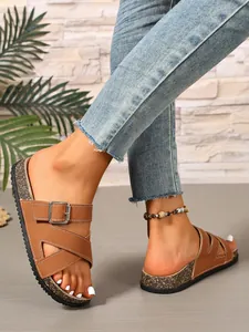 Brown buckled cork slides on feet, casual summer beach sandals for outdoor wear.