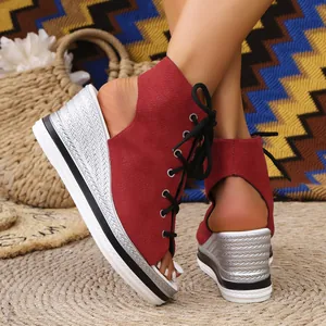 Close-up of red lace-up wedge sandals with silver textured heels and open toe