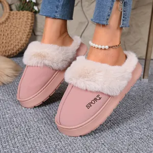 Close-up of pink fuzzy slippers with fur trim and SPORT embroidery on a grey carpet.