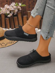 Close-up of stylish black suede slip-on mules featuring front drawstring and thick rubber sole