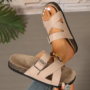 Detailed view showing the beige cork sandals with crossover straps and silver buckle.
