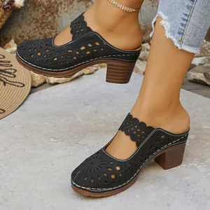 Close-up of stylish black hollow-out block heel mules with elegant laser-cut pattern