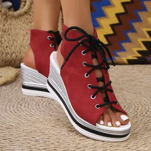 Close-up of red suede peep-toe wedge sandals with black laces and silver platform soles.