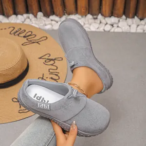 Close-up of grey suede slip-on shoes with drawstring toggle detail in a resort setting.