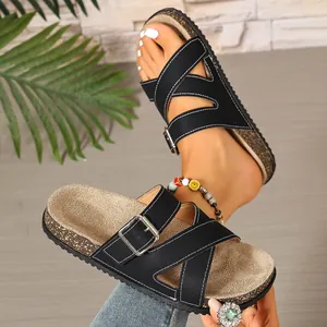 Close-up detail of casual black buckled slide sandals featuring cork-style footbeds