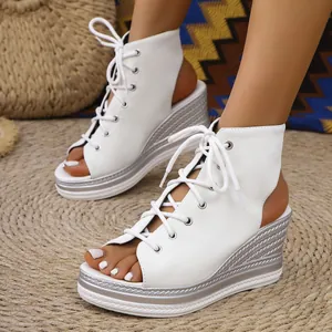 Close-up of stylish white lace-up peep-toe wedge sandals worn on a textured straw mat