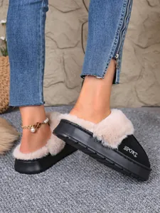 Cozy black indoor outdoor winter slippers with plush beige faux fur trim shown worn on feet