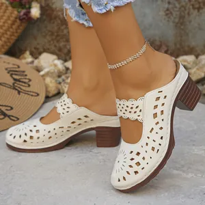 Close-up view of elegant white hollow-out closed-toe mules with chunky wood-grain heels on a model.