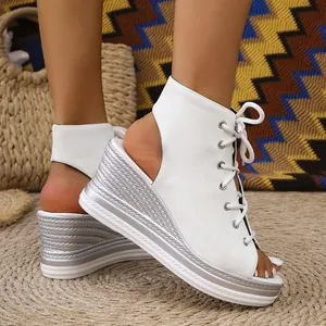Close-up detail of white lace-up wedge sandals with metallic textured platform heel