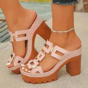 Gros plan de mules à plateforme rose avec boucles dorées et talons blocs aspect bois.
