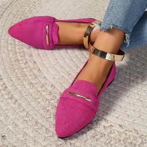 Close-up of fuchsia suede pointed-toe flats worn on feet with gold metallic trim