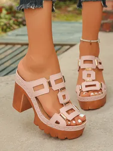Gros plan de mules à plateforme roses avec boucles dorées et hauts talons épais.