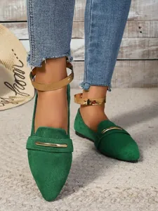 Detailed view of green suede pointed-toe flats with gold ankle straps and metal accents.