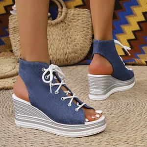 Close-up detail of women's blue denim wedge sandals featuring a stylish white lace-up front