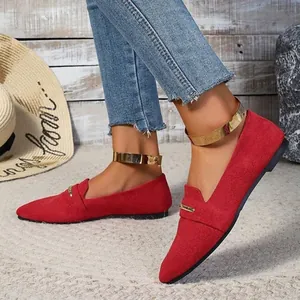 A detailed view of red suede flat shoes featuring elegant gold metallic ankle straps.