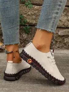 Vista detallada de zapatos planos crema para mujer con suela marrón cosida a mano.