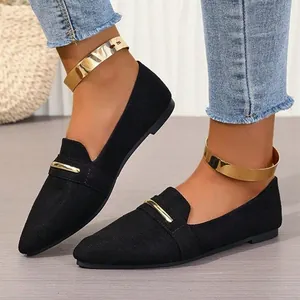 Detail of elegant black suede flat shoes for women featuring stylish gold metal bar and cuffs