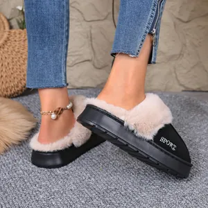 Detailed view of black winter home slippers with soft plush fur trim worn on a grey rug