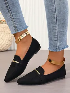 Detail of black pointed-toe flat shoes with elegant gold metal bar and ankle cuffs