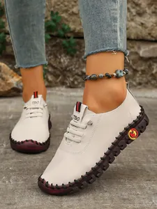 Detalle de mocasines blancos casuales cosidos a mano para mujer con suela de goma duradera