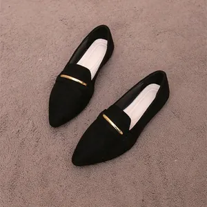 Close-up detail of stylish black suede pointed-toe flats with gold metal bar decoration