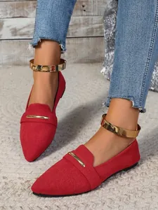 Red suede pointed-toe flats featuring decorative gold metal ankle straps and bar detail