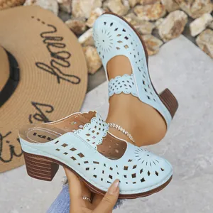 Close-up of light blue hollow-out block heel mules with floral laser-cut design.
