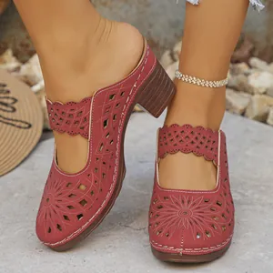Close-up of red hollow-out mule slippers with a chunky high heel and floral pattern