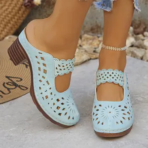 Detailed view of light blue laser-cut heeled mules featuring elegant floral patterns and chunky heels
