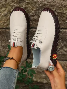 Primer plano de mocasines de cuero blanco cosidos a mano para mujer con suela plana