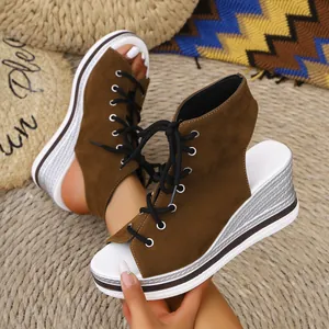 Detail view of brown suede peep-toe wedge sandals with a stylish lace-up front design