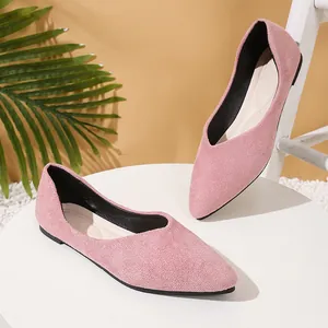 A pair of elegant pink suede pointed-toe flat ballet shoes displayed on a white table.