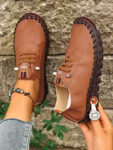 Vista detallada de zapatos planos informales marrones cosidos a mano para mujer.