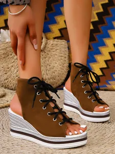 Close-up detail of women's brown suede lace-up wedge sandals with peep-toe design.