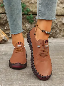 Primer plano de zapatos planos marrones cosidos a mano para mujer con tobillera boho