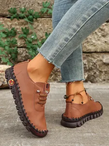 Vista detallada de zapatos planos marrones de piel sintética con costuras a mano.