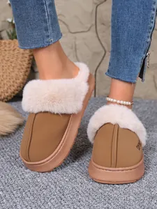 Close-up view of cozy tan winter slippers with a plush faux fur collar on model's feet