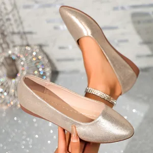 Close-up of elegant champagne gold sparkly pointed-toe flat shoes with glitter texture