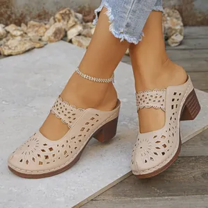 Macro detail showing the intricate laser-cut floral patterns on beige chunky heel mules