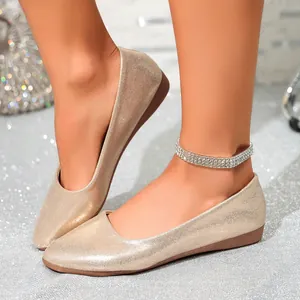 Macro detail of sparkling gold champagne pointed-toe ballet flats worn by a model
